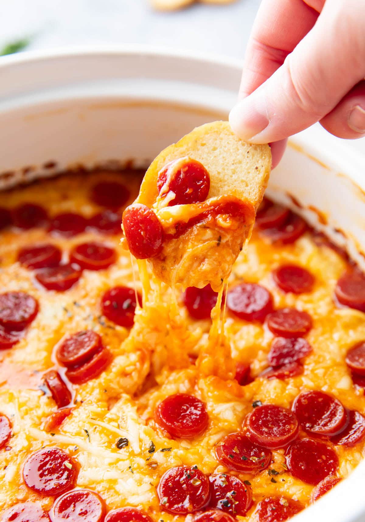 Close up someone scooping this pepperoni pizza dip recipe from a hot dish.