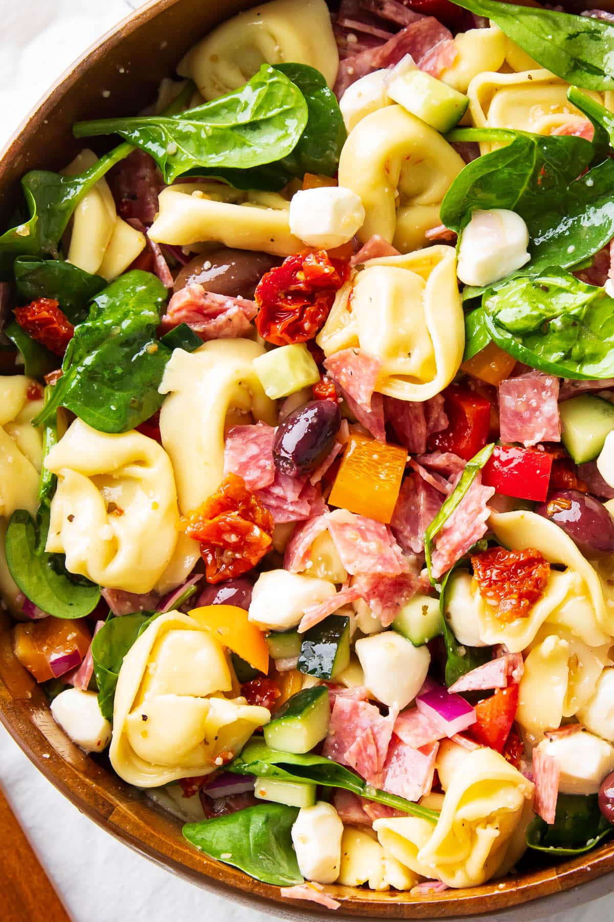 Close up of this tortellini pasta salad in a wooden salad bowl.
