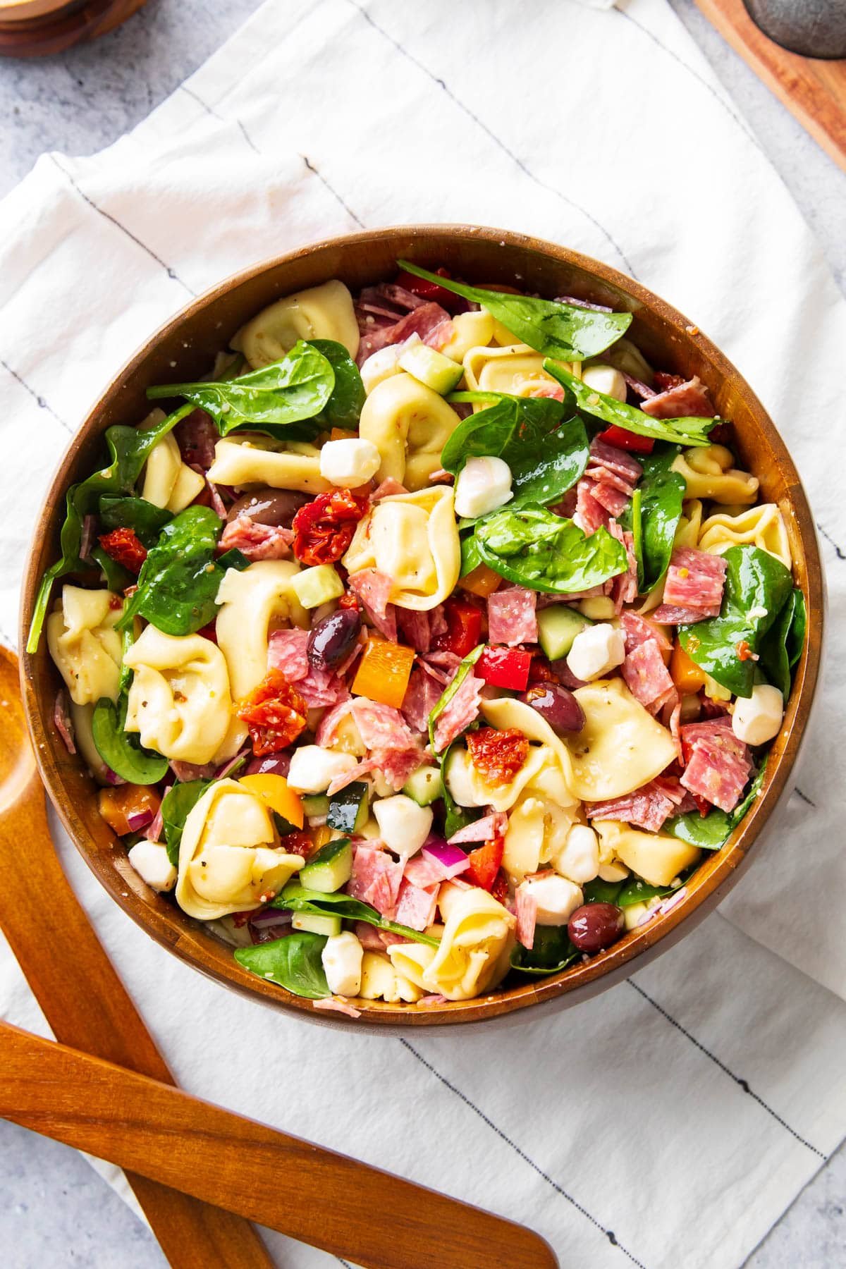 Serving the best tortellini pasta salad in a serving bowl with salad tongs.