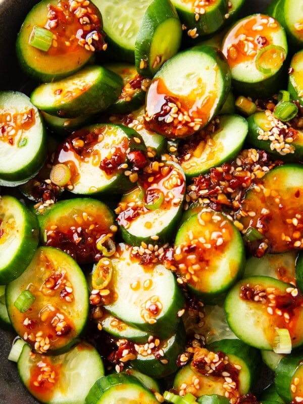 Overhead photos of scallions, sesame, chili, and soy sauce top Asian Cucumber Salad.