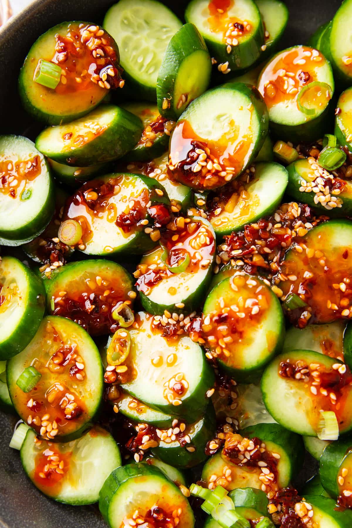 Overhead photos of scallions, sesame, chili, and soy sauce top Asian Cucumber Salad.