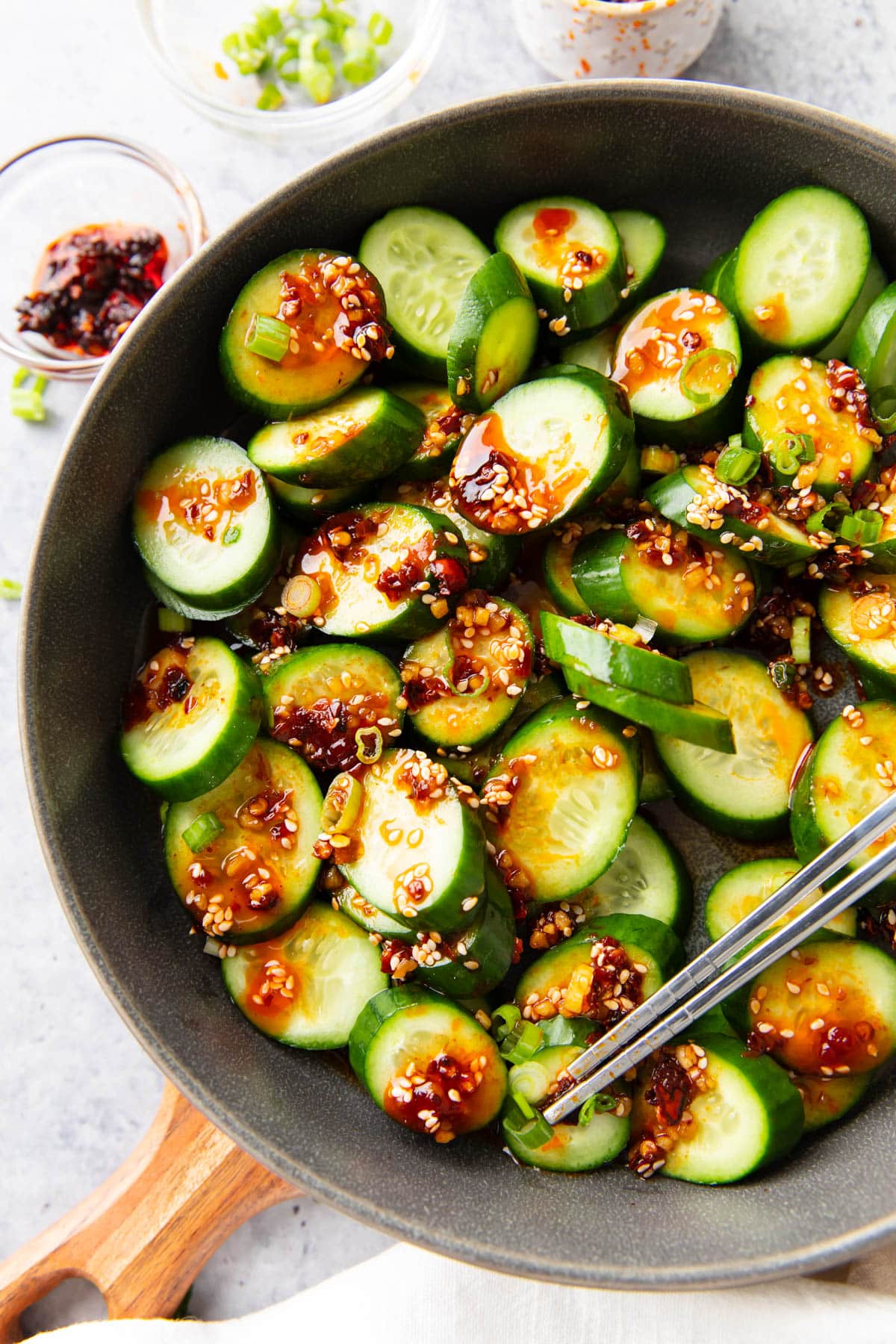 Serving this refreshing Asian side dish packed with veggies in a bowl with sauce, toppings, and chopsticks on the side.