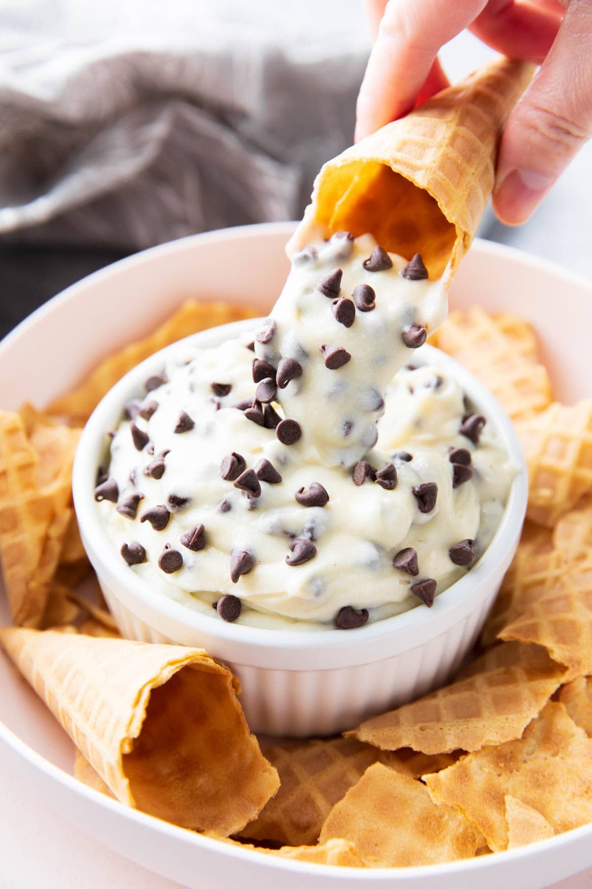 Cannoli dip pouring out to show thickened texture and chocolate chips.