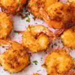 Coconut shrimp fried crispy golden on parchment paper.