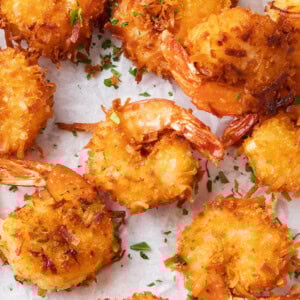 Coconut shrimp fried crispy golden on parchment paper.