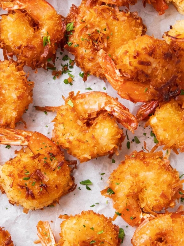 Coconut shrimp fried crispy golden on parchment paper.