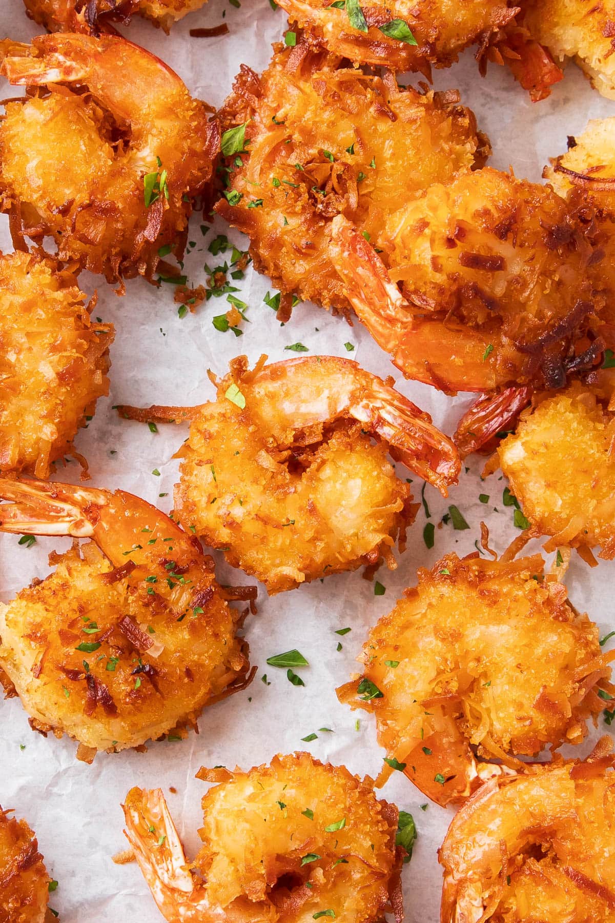 Coconut shrimp fried crispy golden on parchment paper.