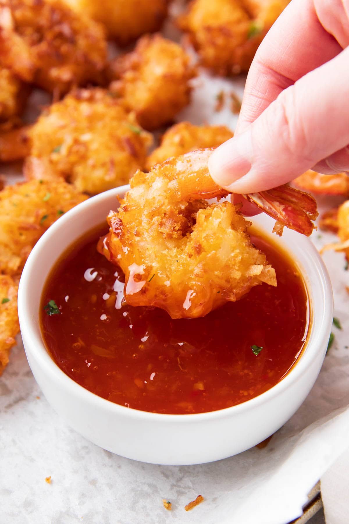 A hand dipping this seafood appetizer into a bowl of easy dipping sauce.