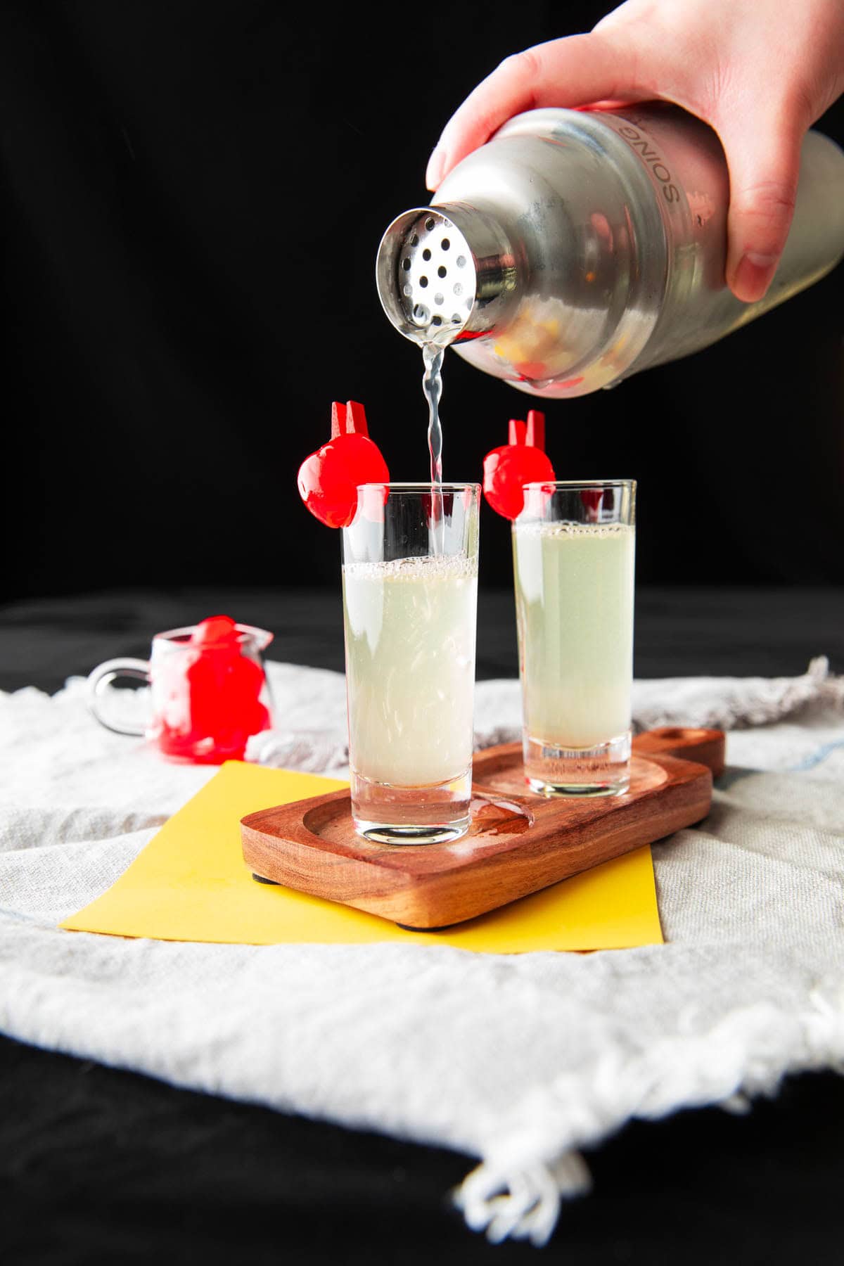 A hand pouring the chilled vodka mixture into a shot glass.