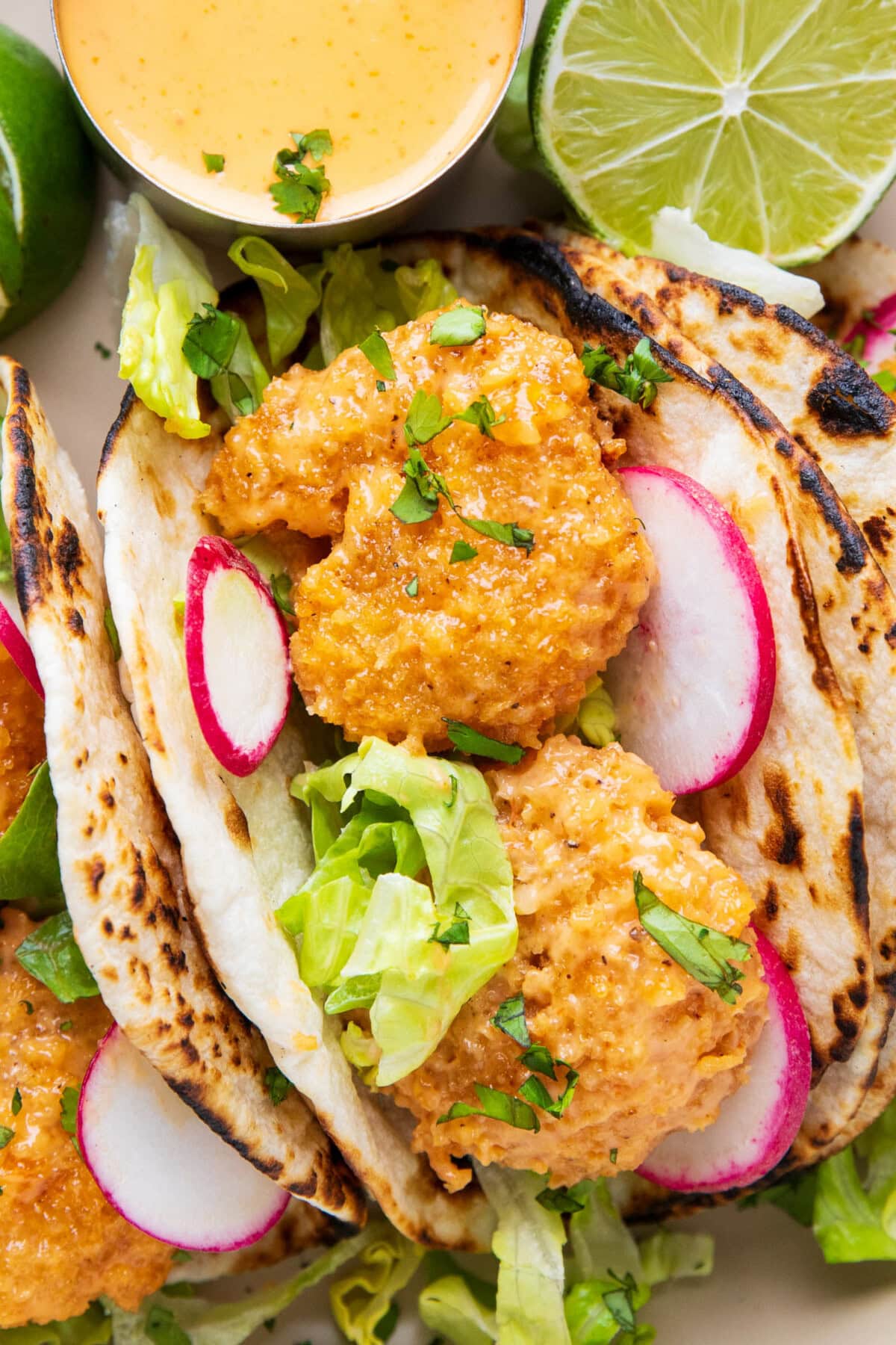 saucy bang bang shrimp packs taco shells with fresh veggies, lime, and sweet chili mayo sauce