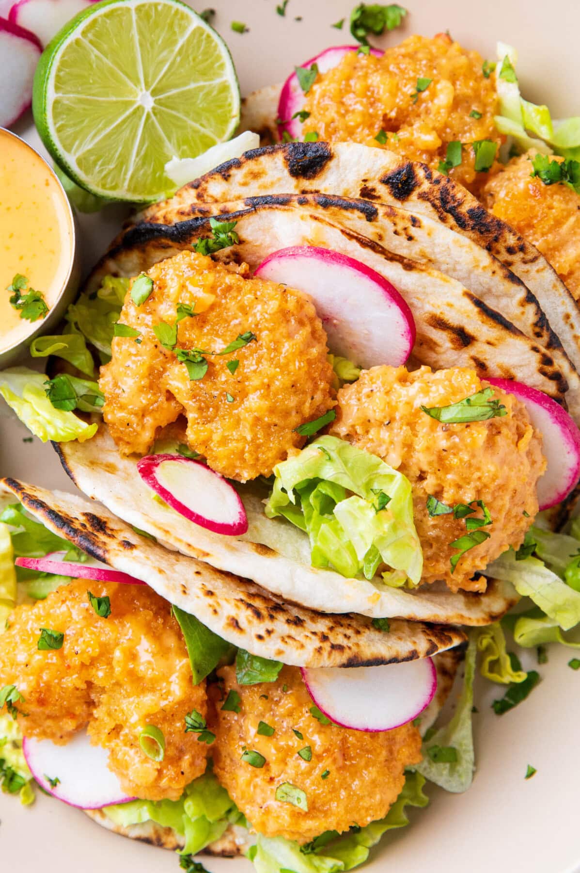 this bang bang taco recipe includes generously sauced shrimp is tucked in a charred taco with fresh lettuce, a squeeze of lime, and lots of bang bang sauce