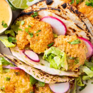 this bang bang taco recipe includes generously sauced shrimp is tucked in a charred taco with fresh lettuce, a squeeze of lime, and lots of bang bang sauce