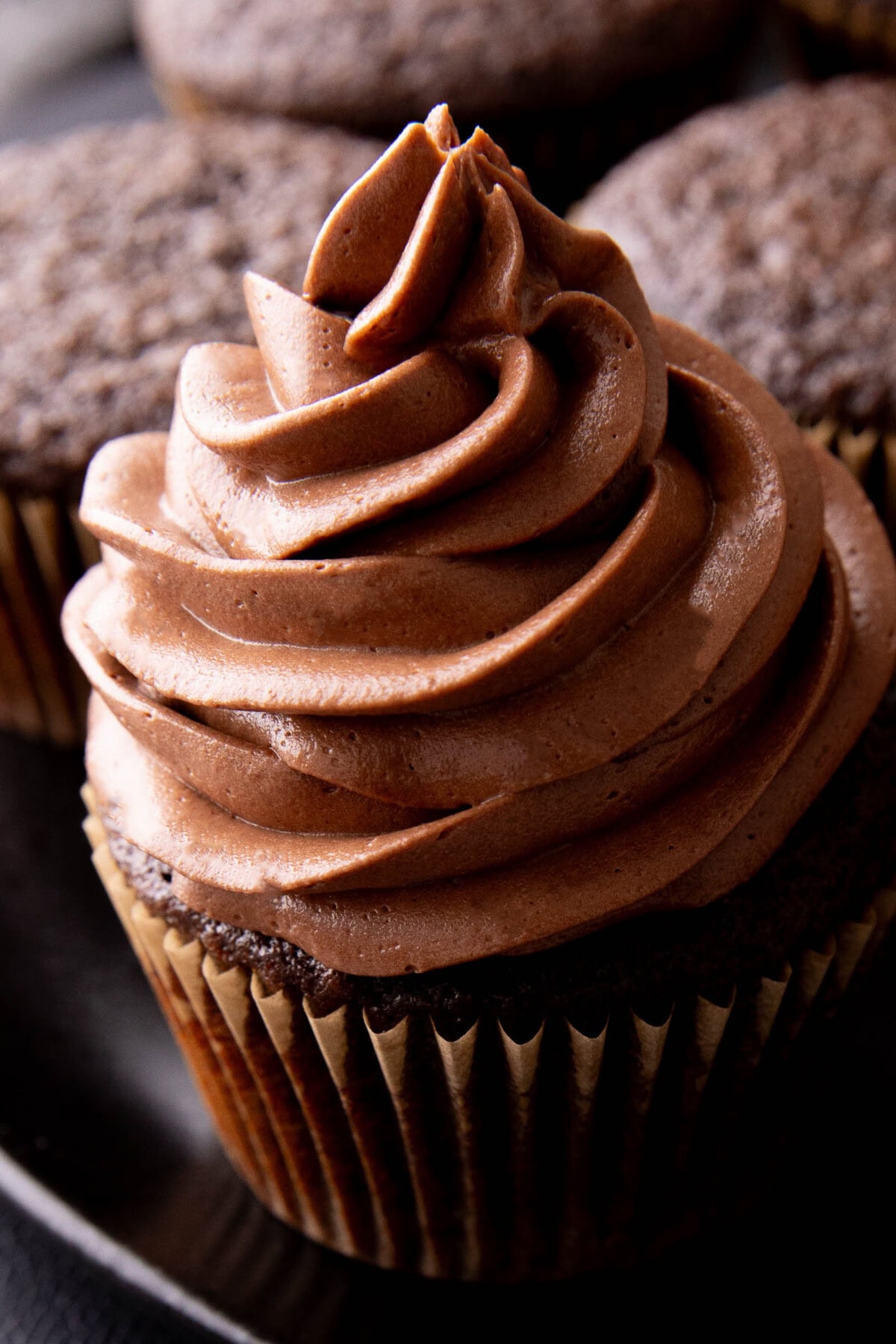 close up of creamy chocolate frosting on top of a cupcake