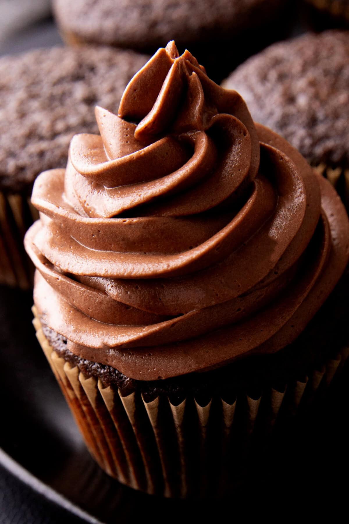 Close up of rich chocolate frosting that's homemade and made with cocoa powder piped on a cupcake.