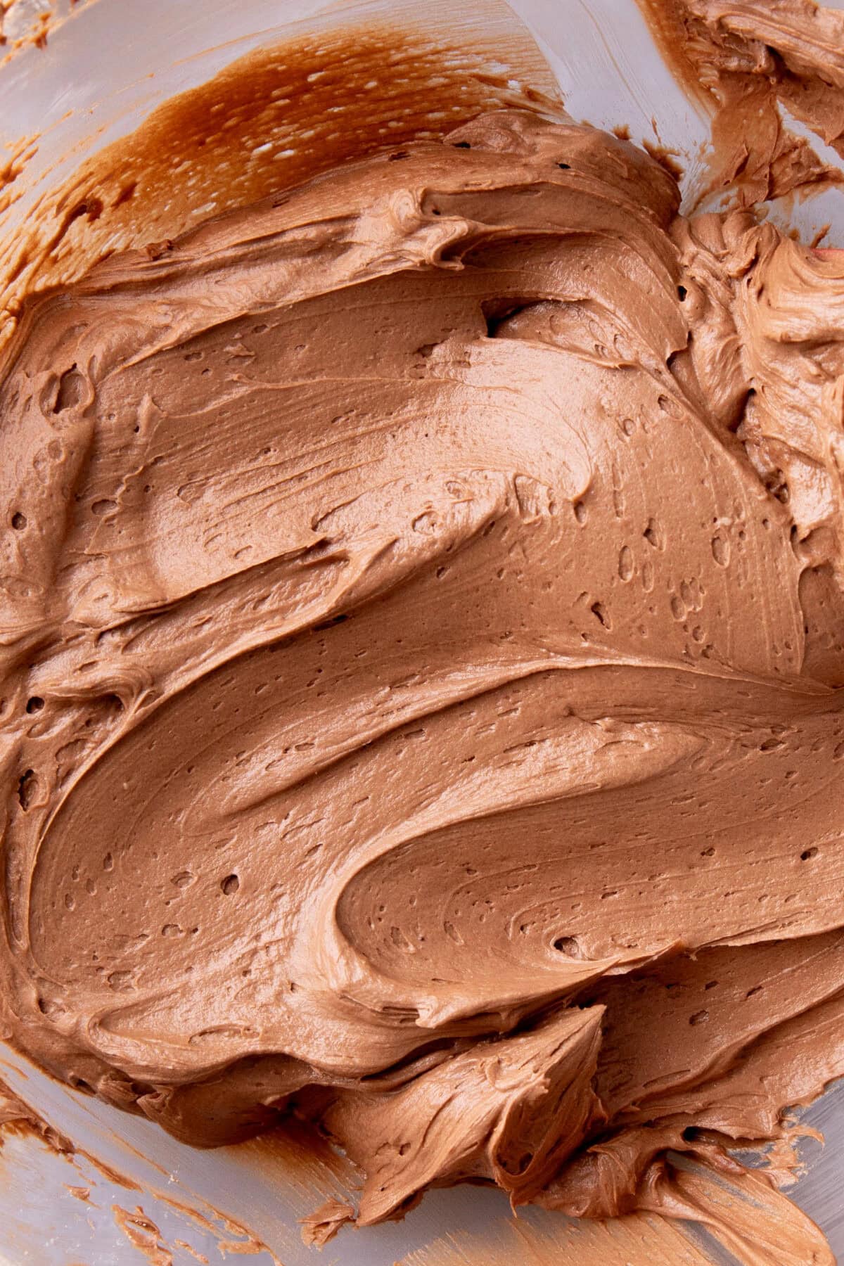 close up of thick, fluffy homemade chocolate frosting whipped in a bowl.