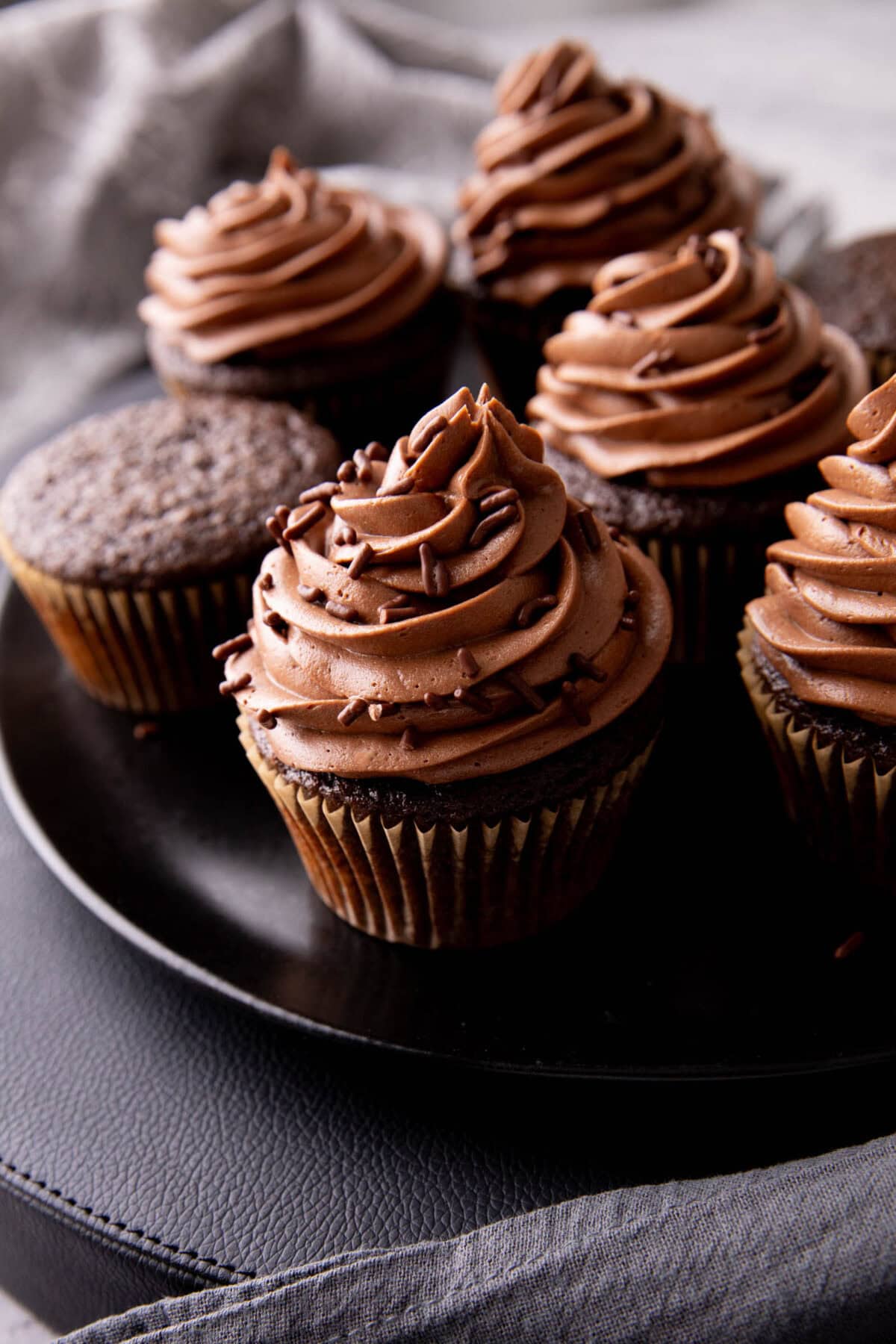 serving platter filled with moist chocolate cupcakes topped with frosting and sprinkles