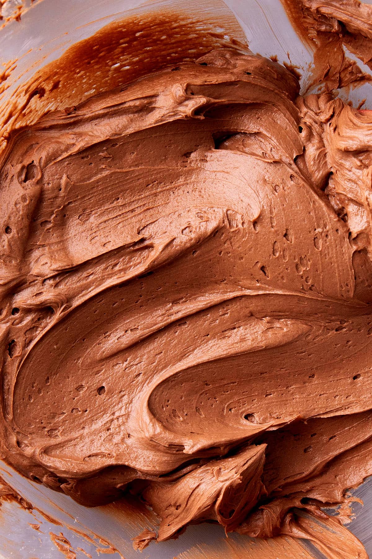 Not too sweet chocolate frosting is whipped in a bowl, blending cocoa powder and confectioners sugar until smooth.
