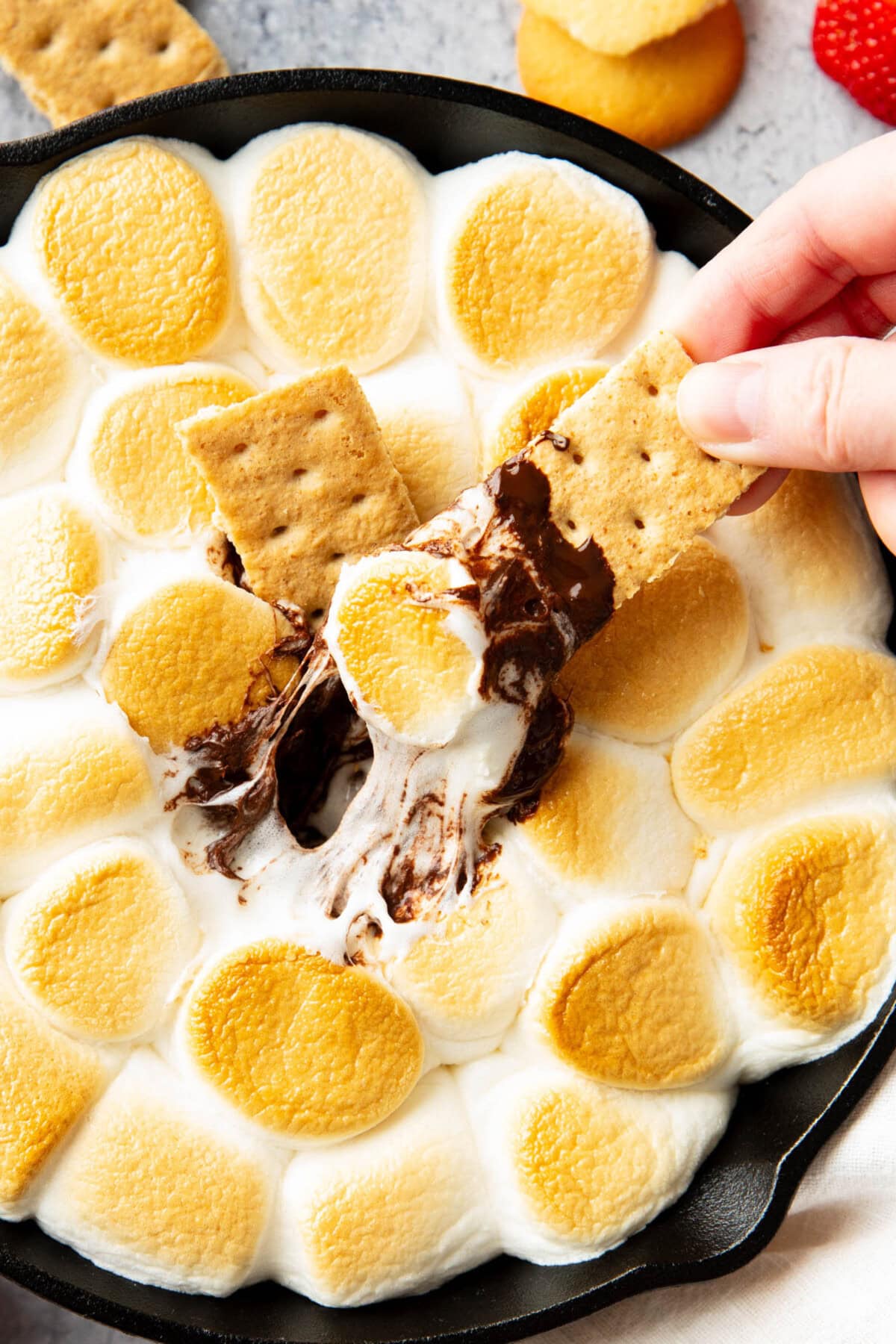 Hand dipping a graham cracker in S'mores Dip
