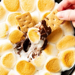 Hand dipping a graham cracker in S'mores Dip