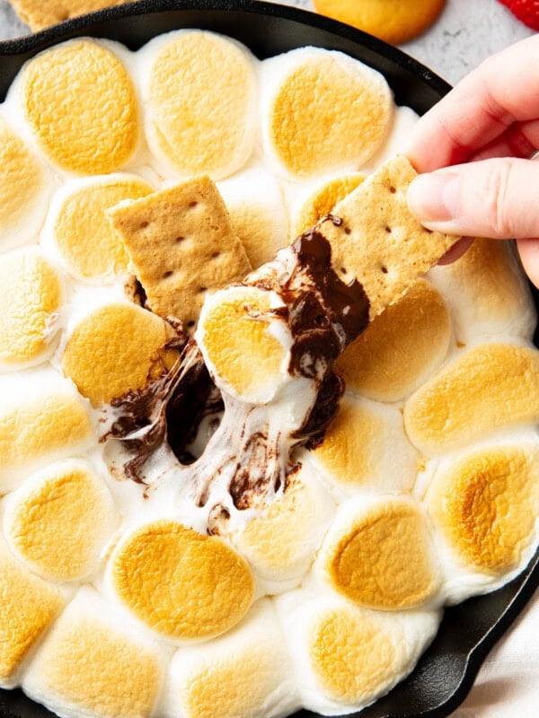 Hand dipping a graham cracker in S'mores Dip