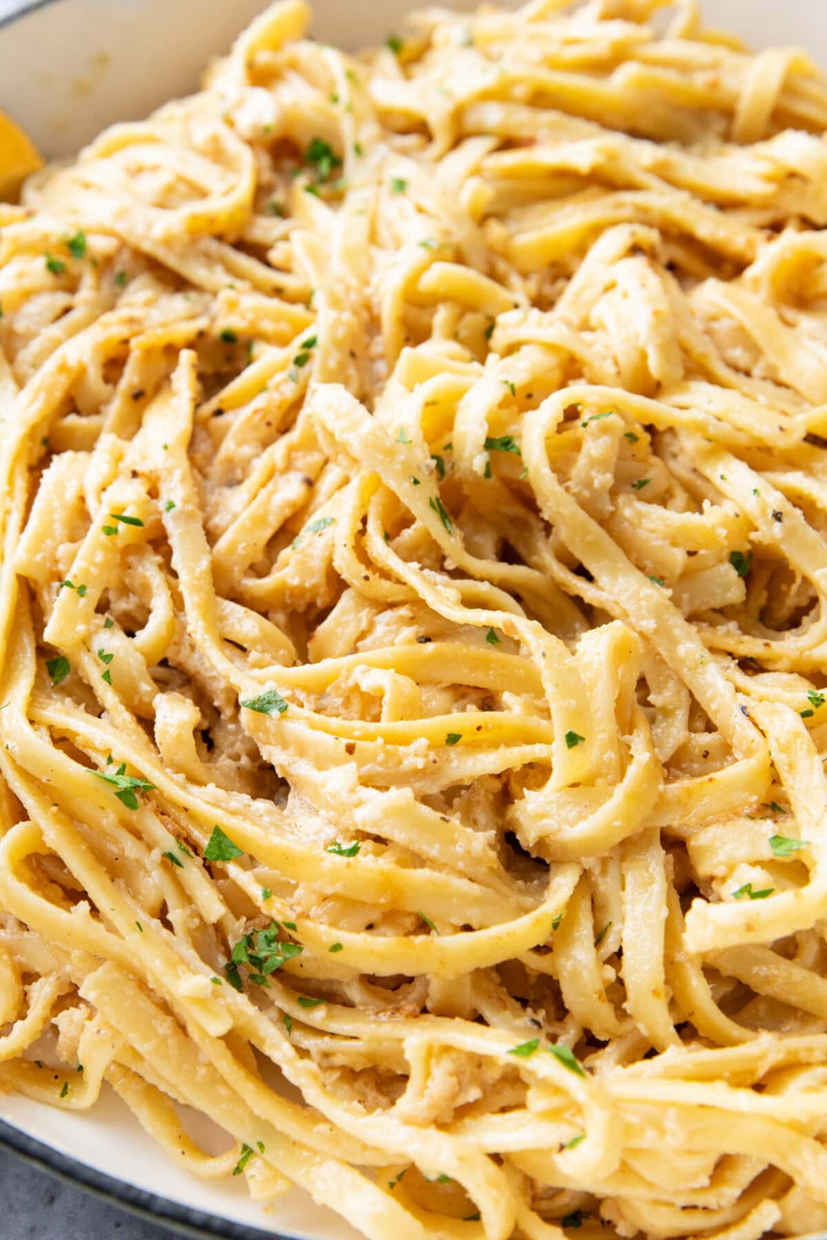 close up of this fettuccine Alfredo recipe shows al dente pasta coated in creamy, garlicky Alfredo sauce made with butter, heavy cream and Parmesan in a large skillet