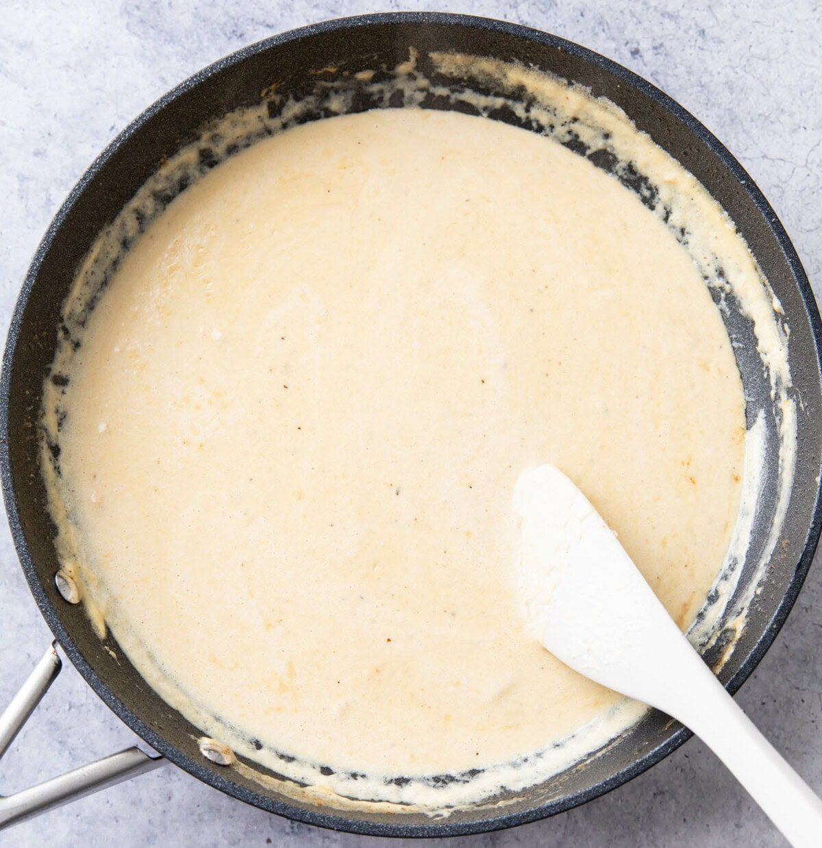 One photo showing How to Make Alfredo Sauce - stirring sauce in a large pan