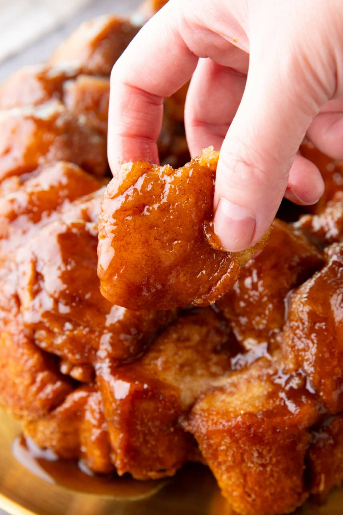 Someone pulling apart this homemade monkey bread by grabbing a sweet biscuit piece from the center