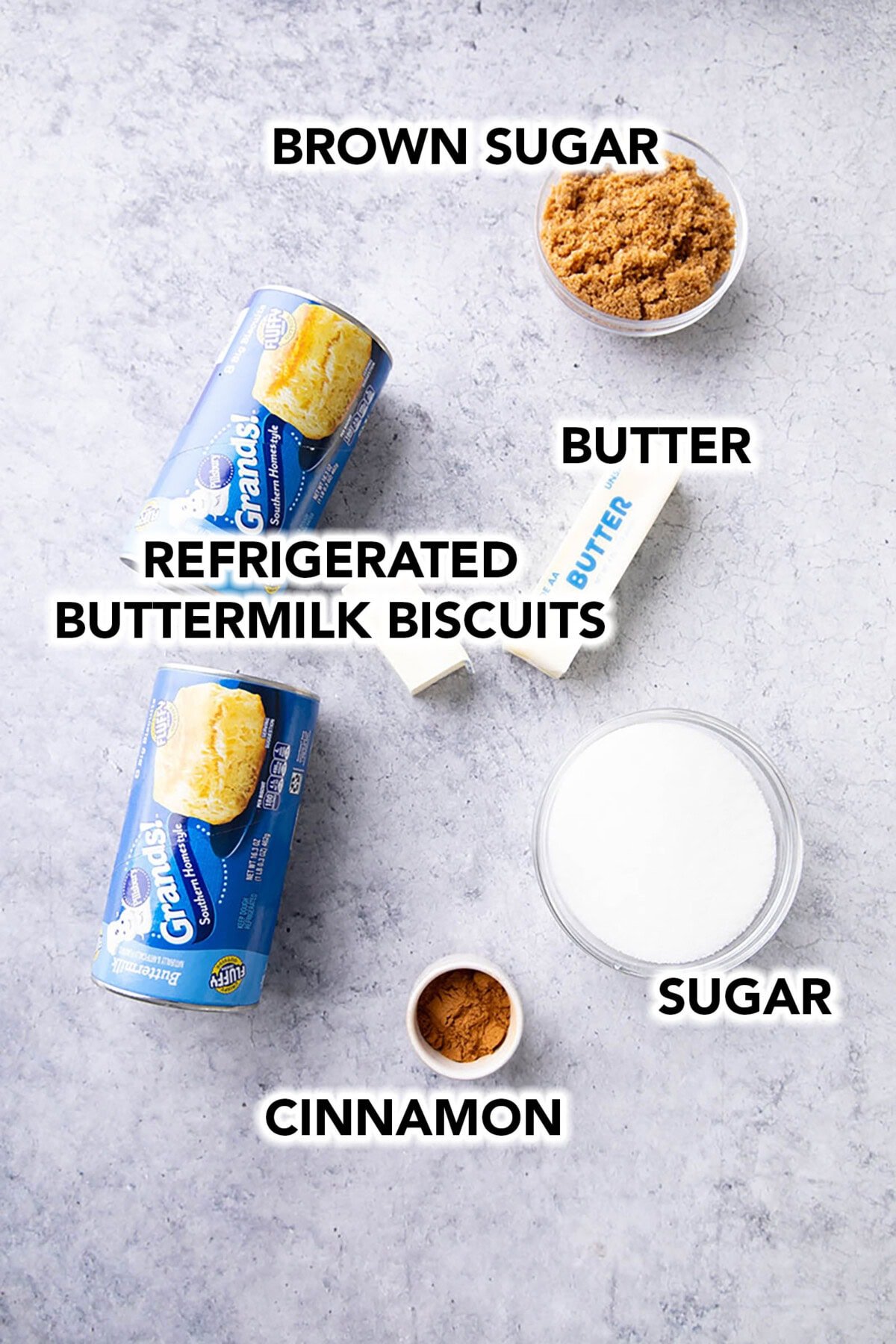 Easy Monkey Bread recipe ingredients in prep bowls including butter, brown sugar, refrigerated buttermilk biscuits, cinnamon, and granulated sugar