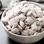 Bowl filled with Muddy Buddies coated in powdered sugar, chocolate and peanut butter