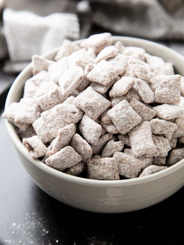 Bowl filled with Muddy Buddies coated in powdered sugar, chocolate and peanut butter