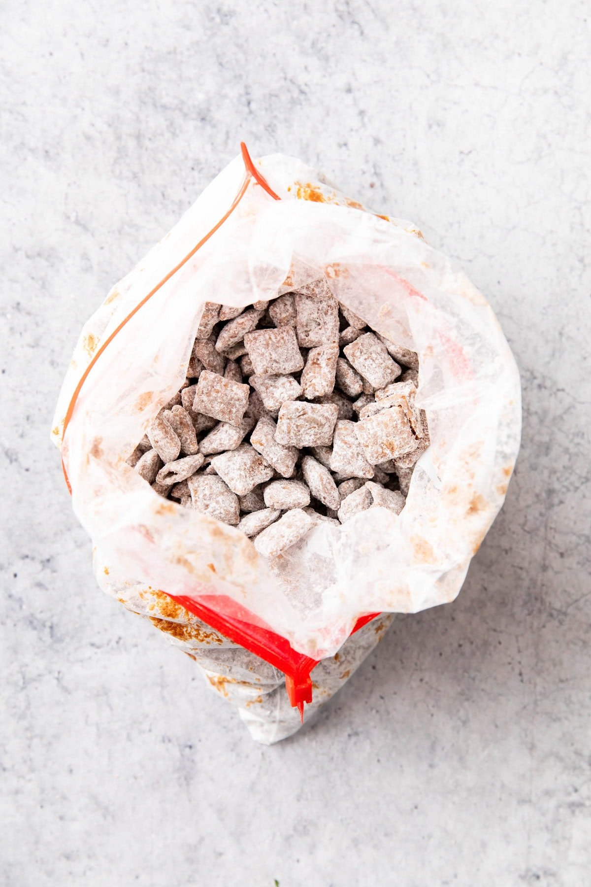 A photo showing How to Make Muddy Buddies - cereal completely tossed and coated in powdered sugar in a zip top gallon bag