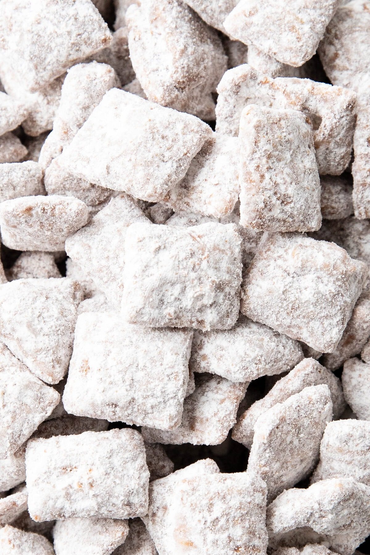 Close up of powder sugar-coated Puppy Chow snack mix to show crunchy texture and sweetness