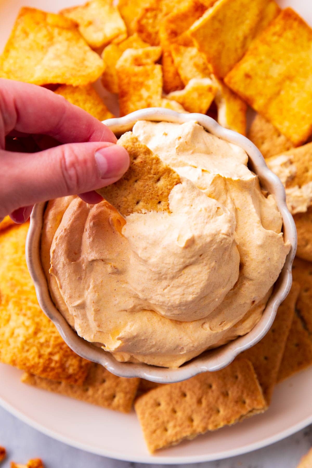 Someone dipping a graham cracker into this pumpkin fluff recipe for dessert.