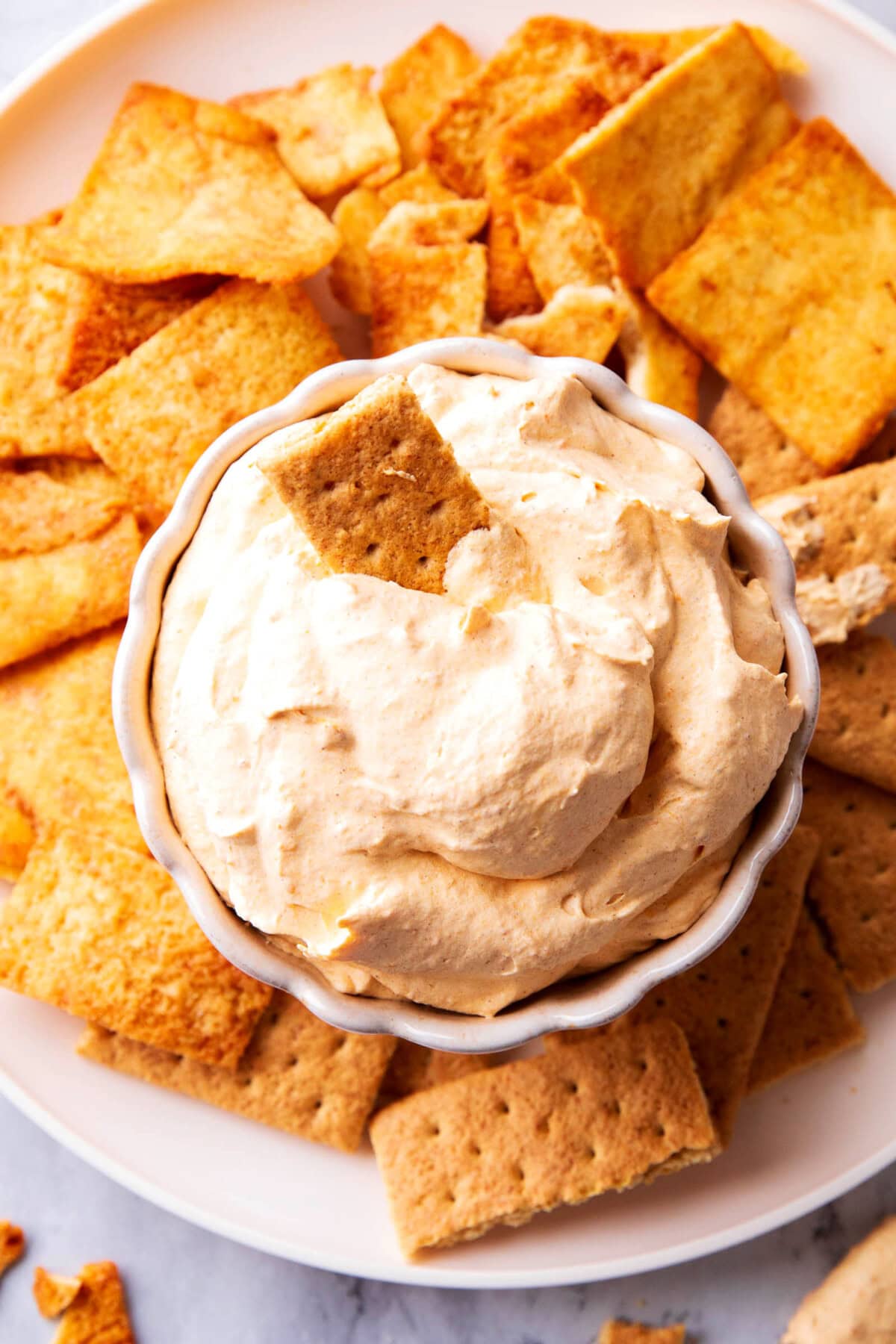 Pumpkin Fluff Dip is fluffy and airy with a whipped texture served in a bowl with graham crackers and sprinkled with pumpkin pie spice