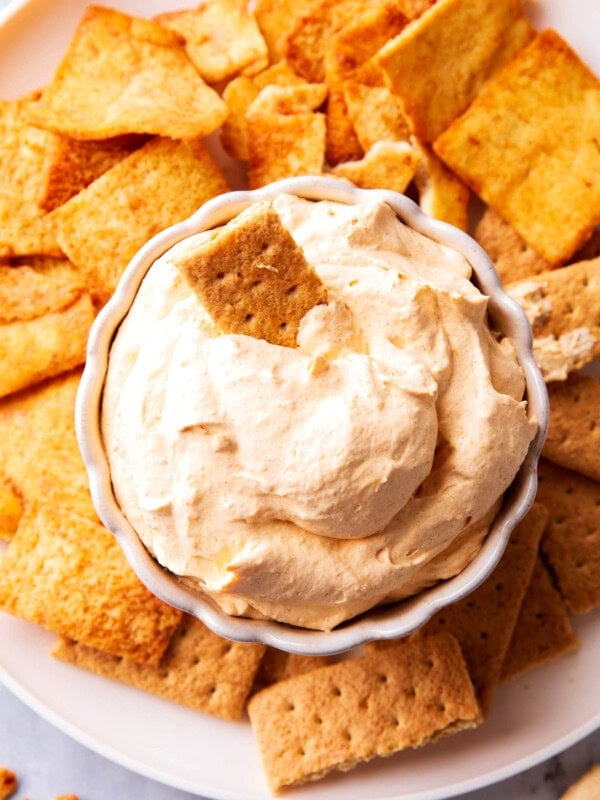 Pumpkin Fluff Dip is fluffy and airy with a whipped texture served in a bowl with graham crackers and sprinkled with pumpkin pie spice
