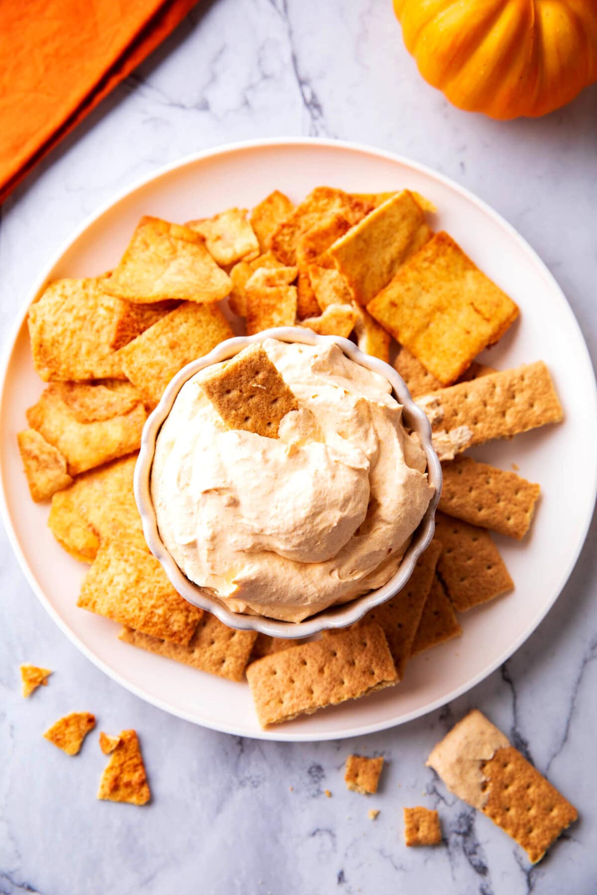 Pumpkin fluff dip served with pita chips, a pumpkin nearby, and other fall dessert table decor
