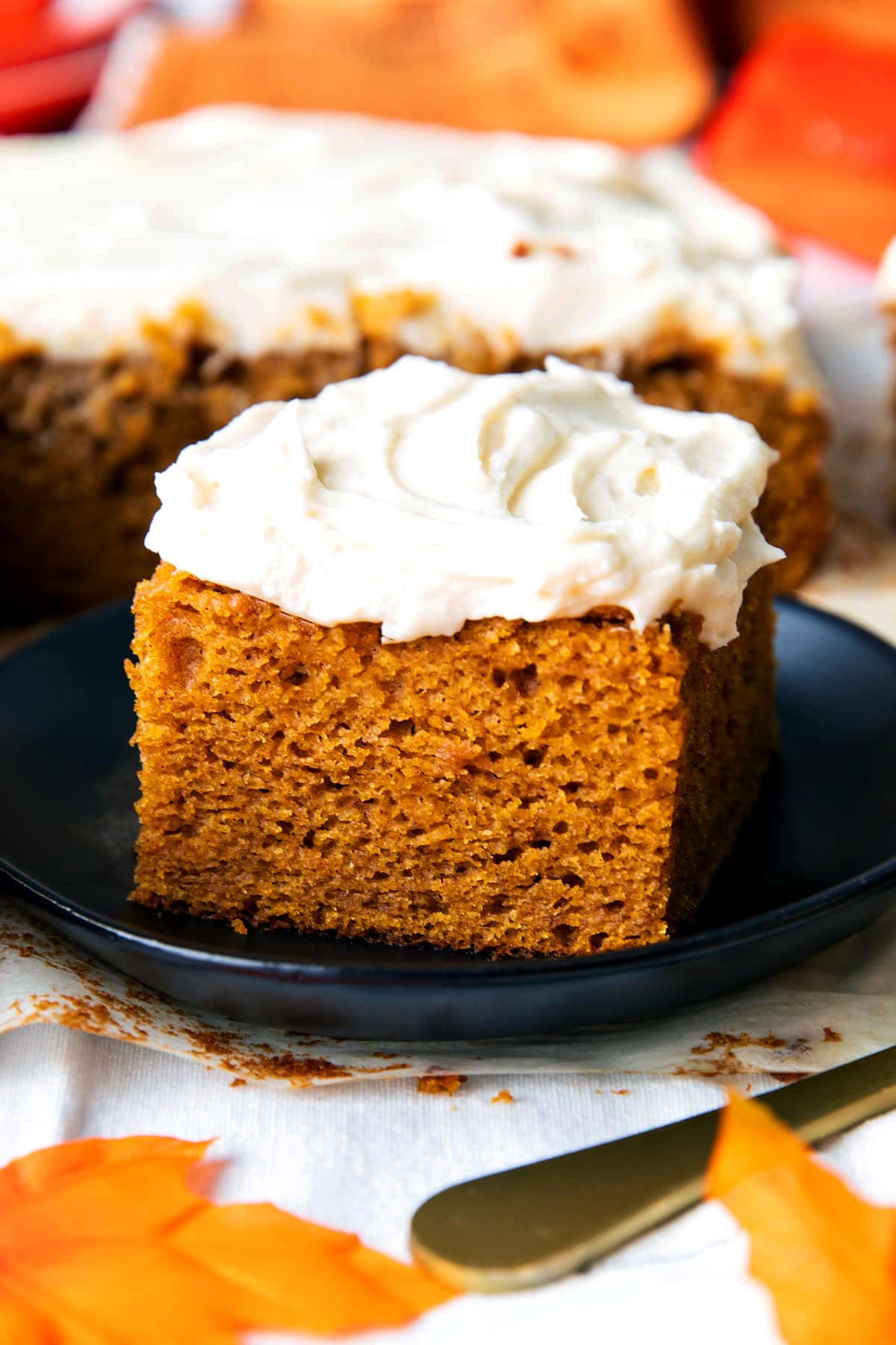 Close up of a slice of this pumpkin spice cake with cream cheese frosting to show soft and moist crumb with rich frosting.