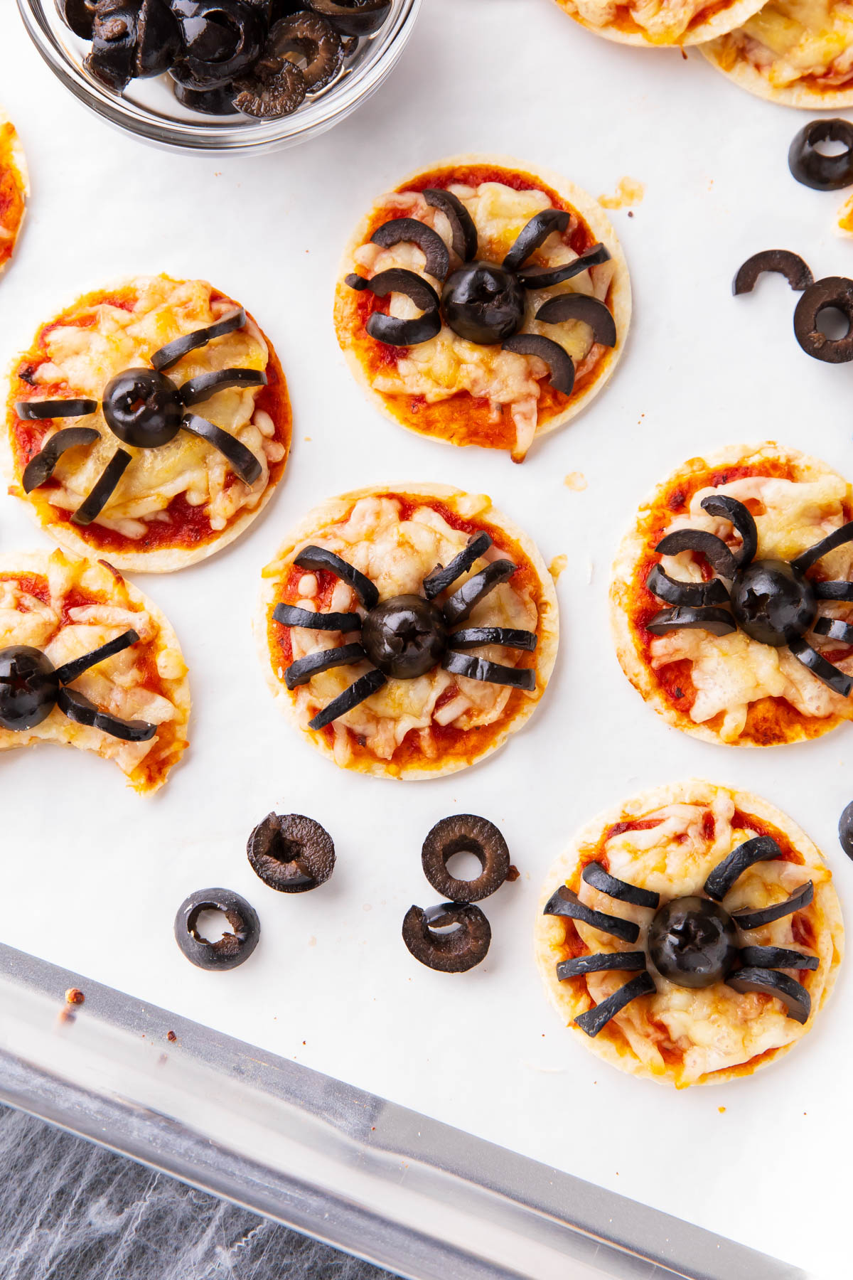 Halloween party pizza on a lined baking sheet with pizza toppings