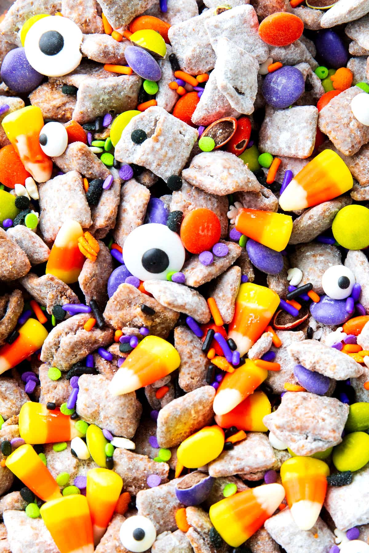 close up of Halloween puppy chow recipe to show crunchy Chex mix cereal coated in peanut butter, powdered sugar and chocolate.