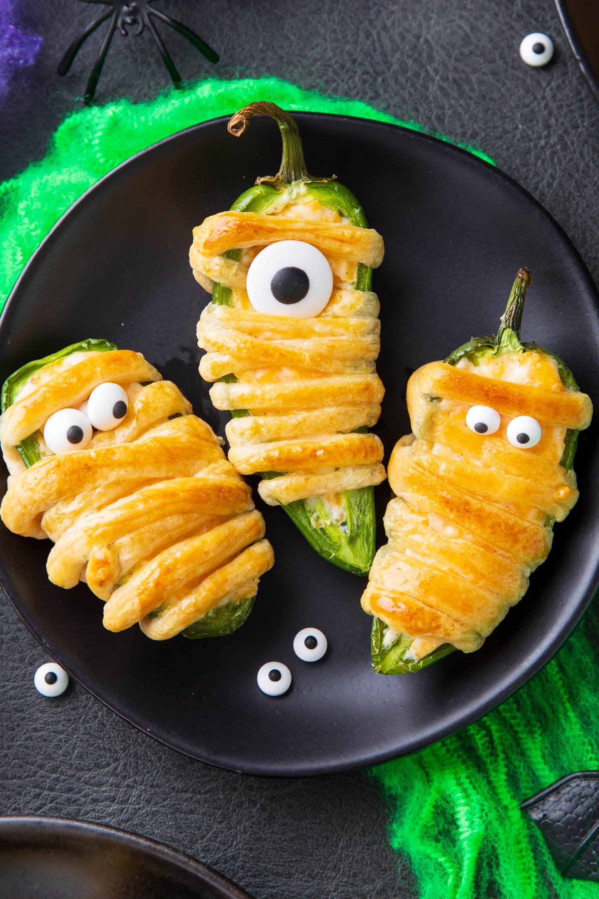 Close up of golden brown crescent wrapped mummy jalapeno poppers filled with cream cheese as a great Halloween appetizer.