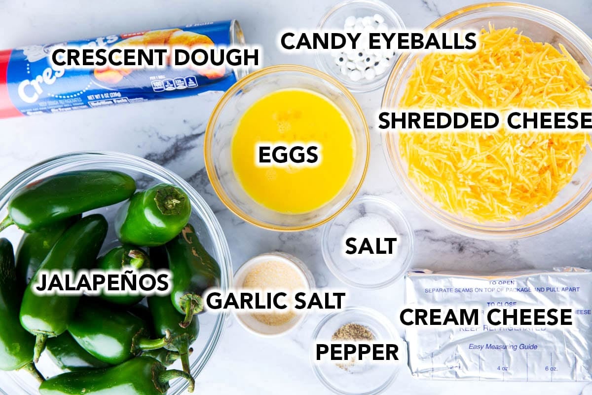 Mummy jalapeno poppers ingredients include fresh jalapenos, eggs, cheese, cream cheese, seasonings, crescent roll dough, and googly eyes.