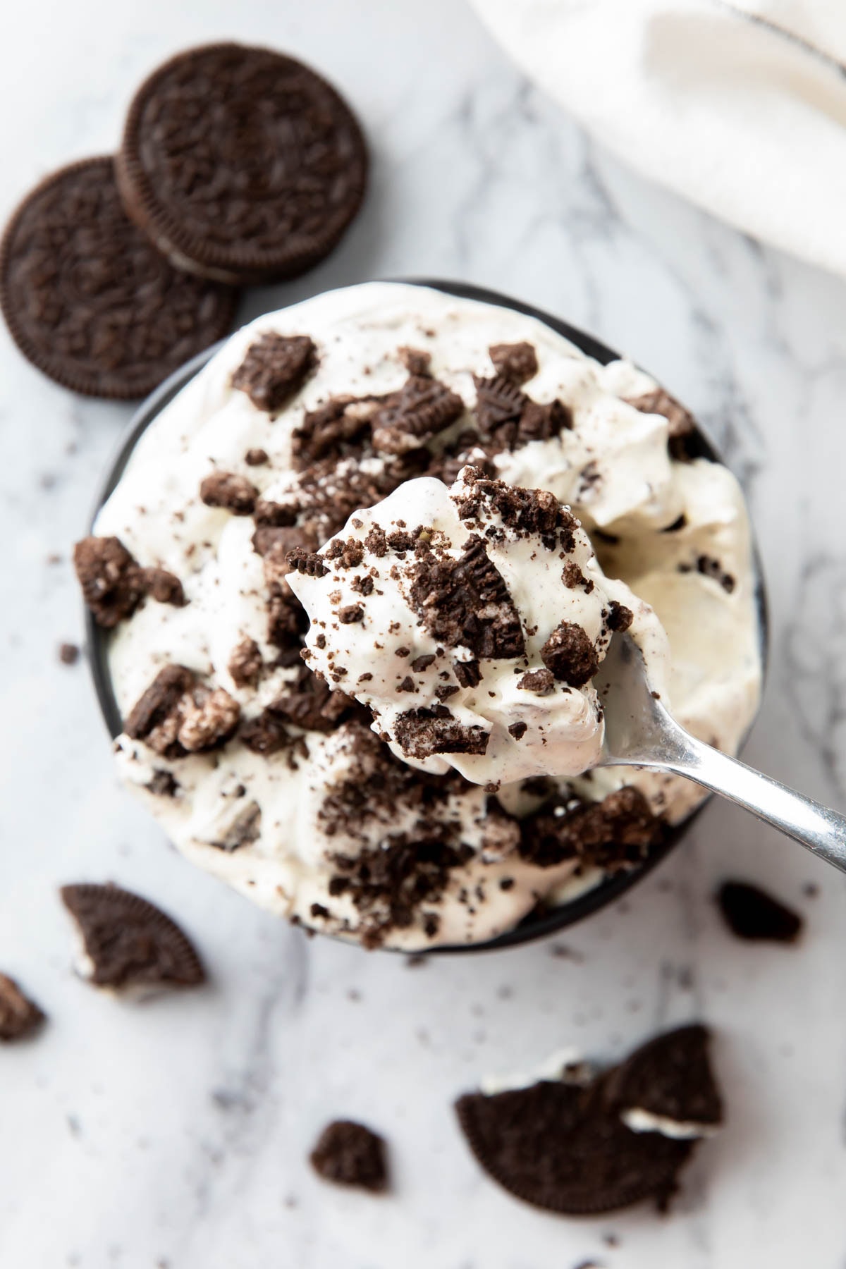 Fluffy Oreo cookie fluff salad on a spoon over a bowl of this dessert dip recipe topped with crushed Oreo cookies