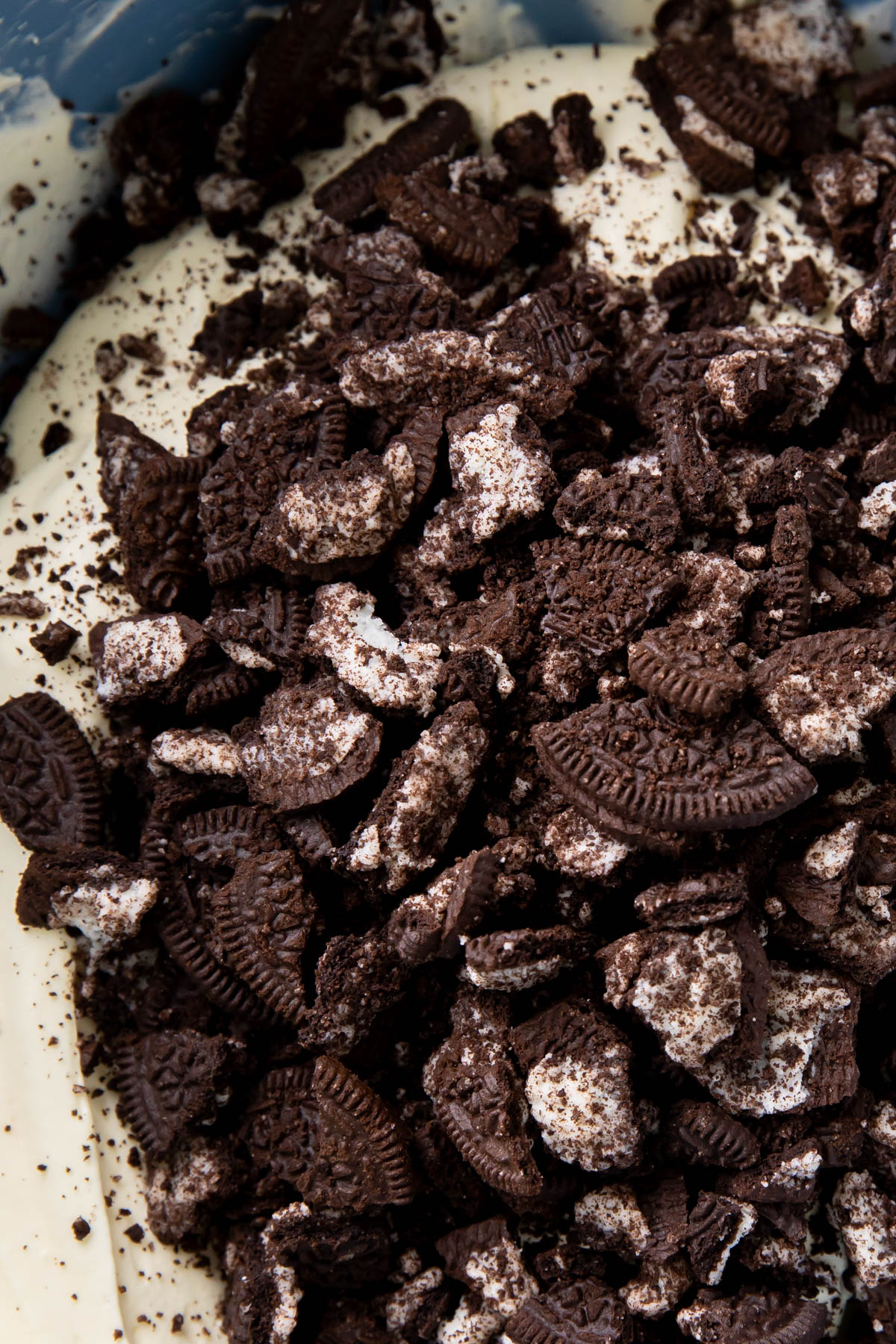 close up of crushed Oreo cookies atop whipped topping mixture