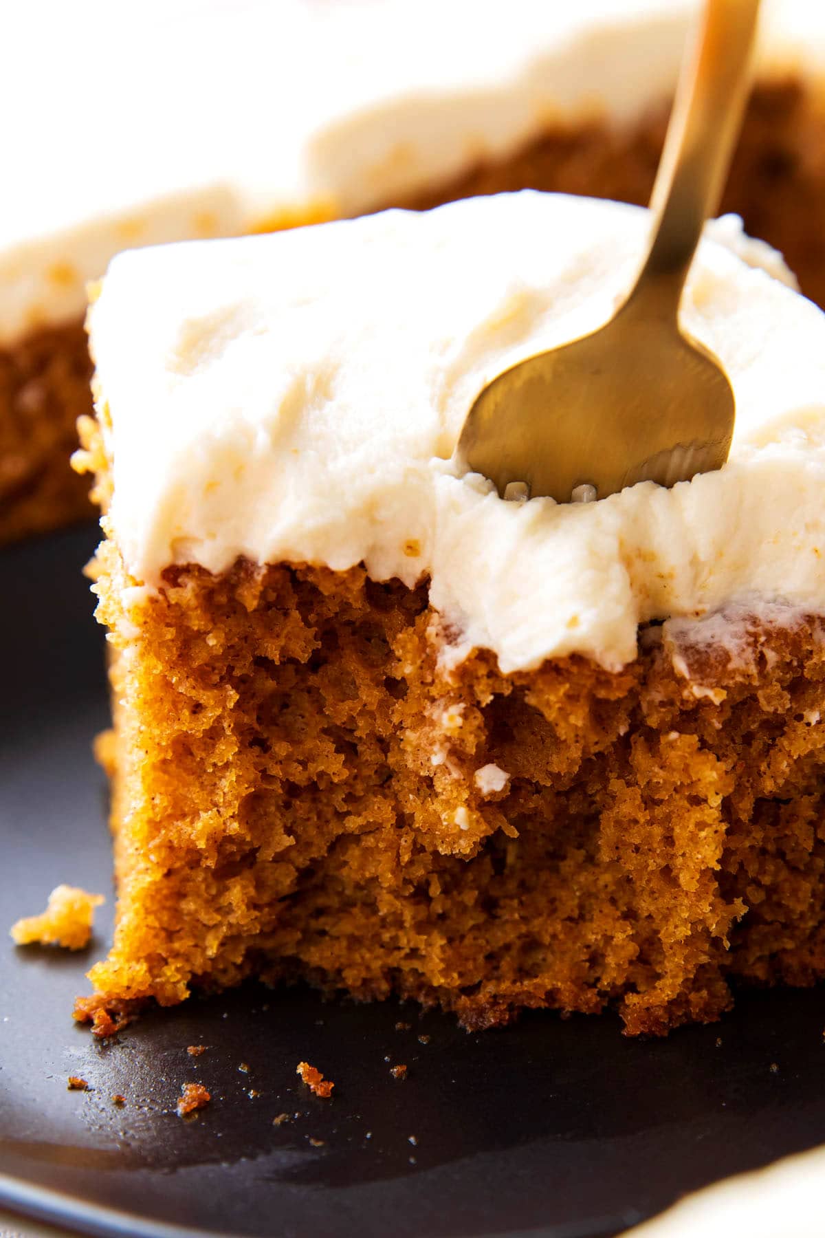 Close up of a fork digging into a slice of this pumpkin cake recipe.