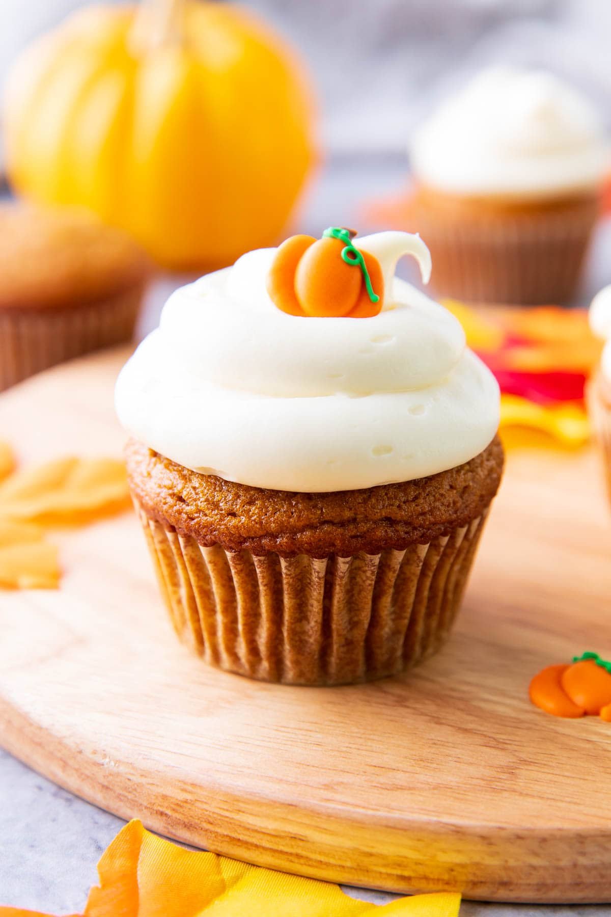 Pumpkin cupcakes with a pumpkin topper atop lots of cream cheese frosting