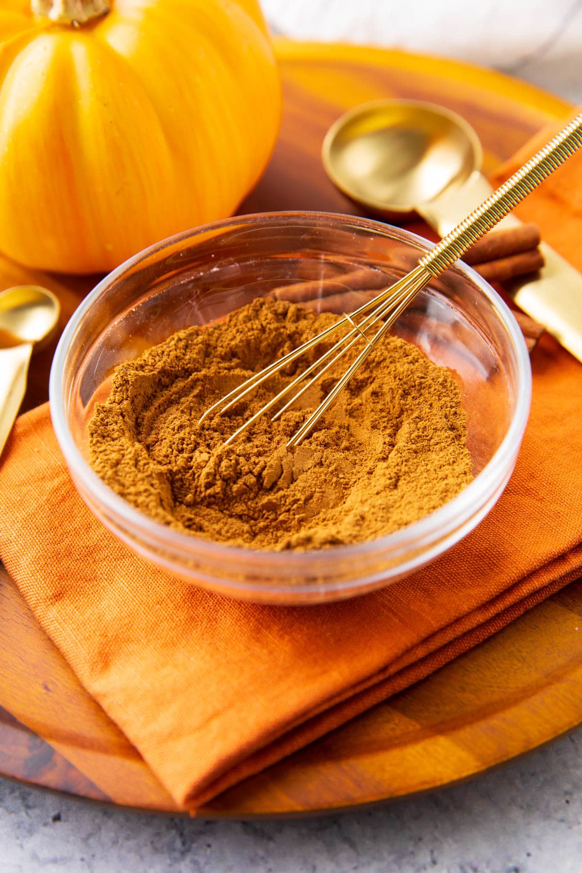 A gold whisk sits in a bowl of this diy pumpkin pie spice.