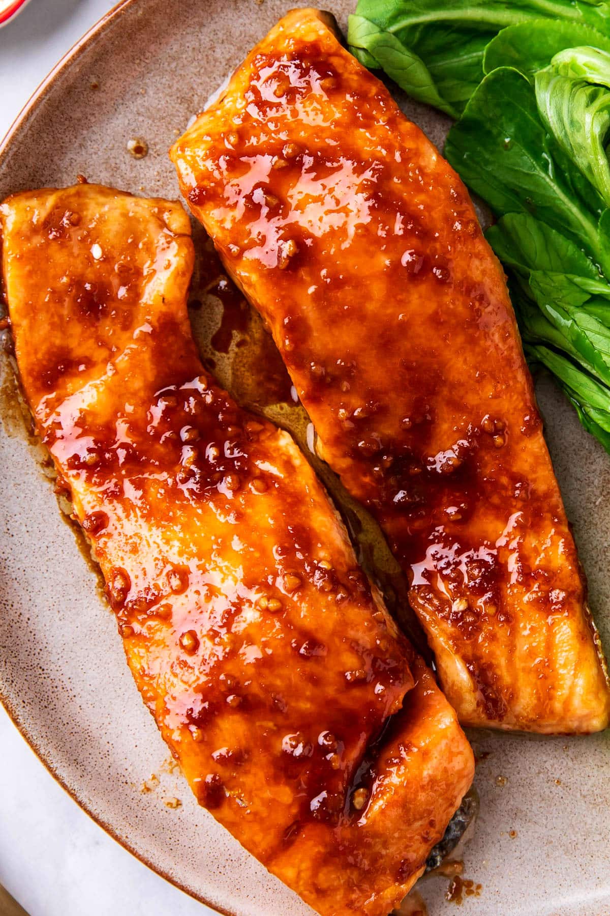 Close up of Asian baked salmon to show the sweet and spicy Asian-inspired sauce and perfectly cooked texture of this easy fish recipe.