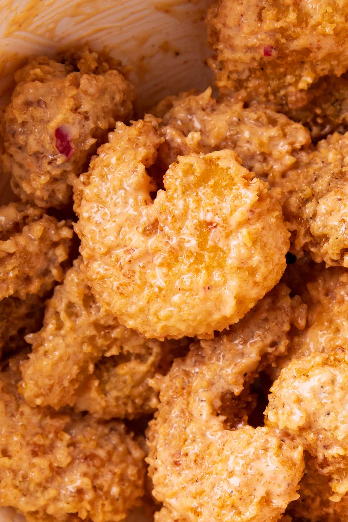 Close up of copycat bang bang shrimp tossed in a mixing bowl with creamy and sweet bang bang sauce made with mayo.