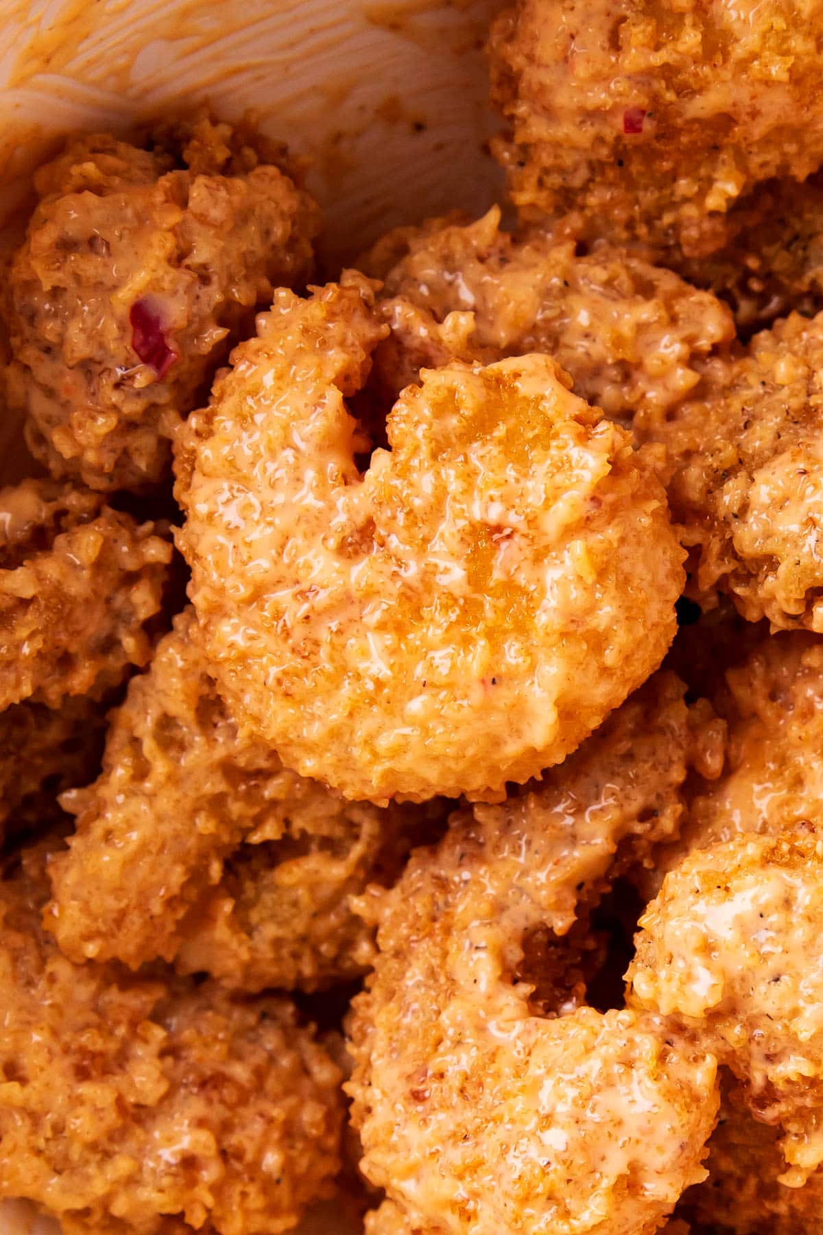 Close up of copycat bang bang shrimp tossed in a mixing bowl with creamy and sweet bang bang sauce made with mayo.