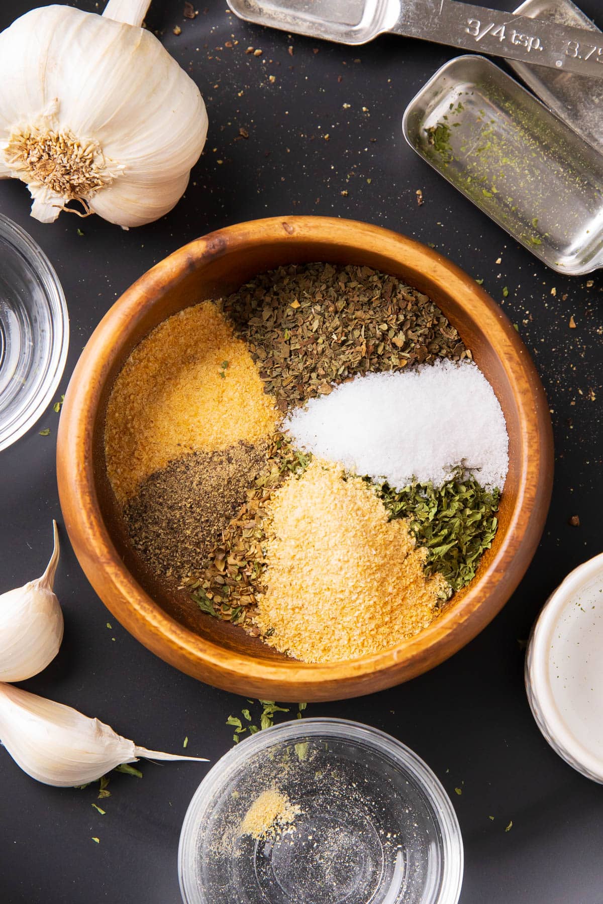 Close up of garlic powder, dried parsley, basil, oregano, onion powder neatly arranged in a spice bowl.